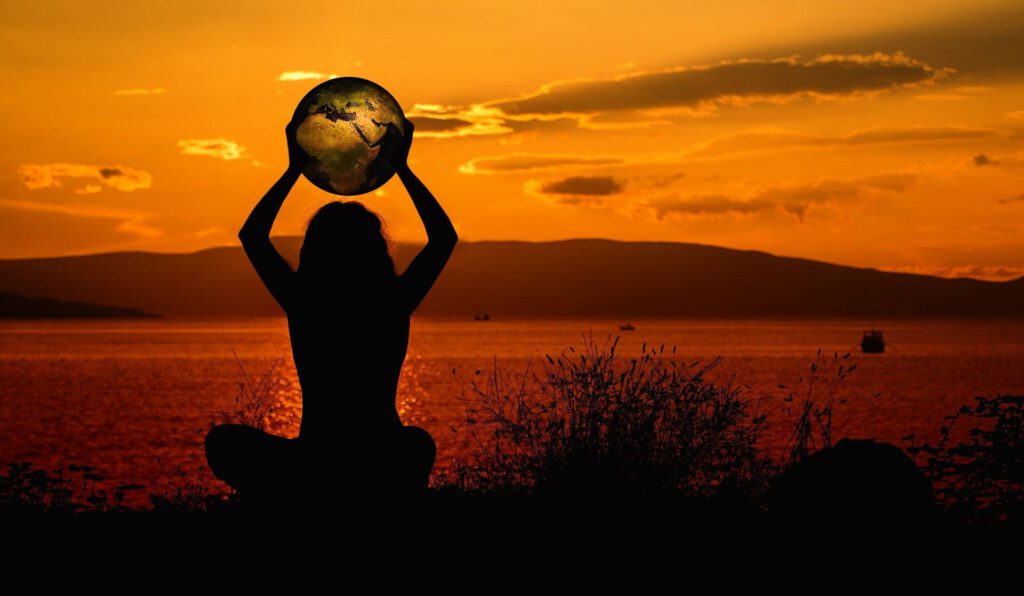 Frau mit Weltkugel im Sonnenuntergang